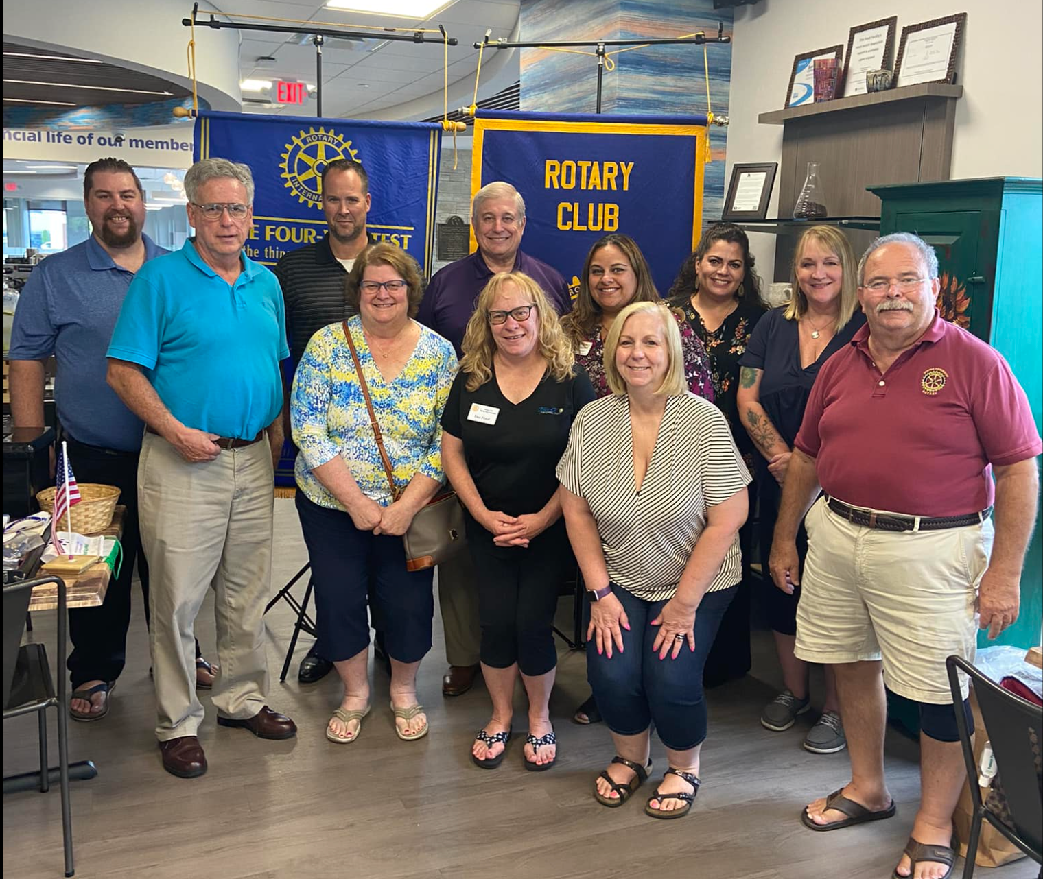 A group of people are posing for a picture in front of a rotary club banner.