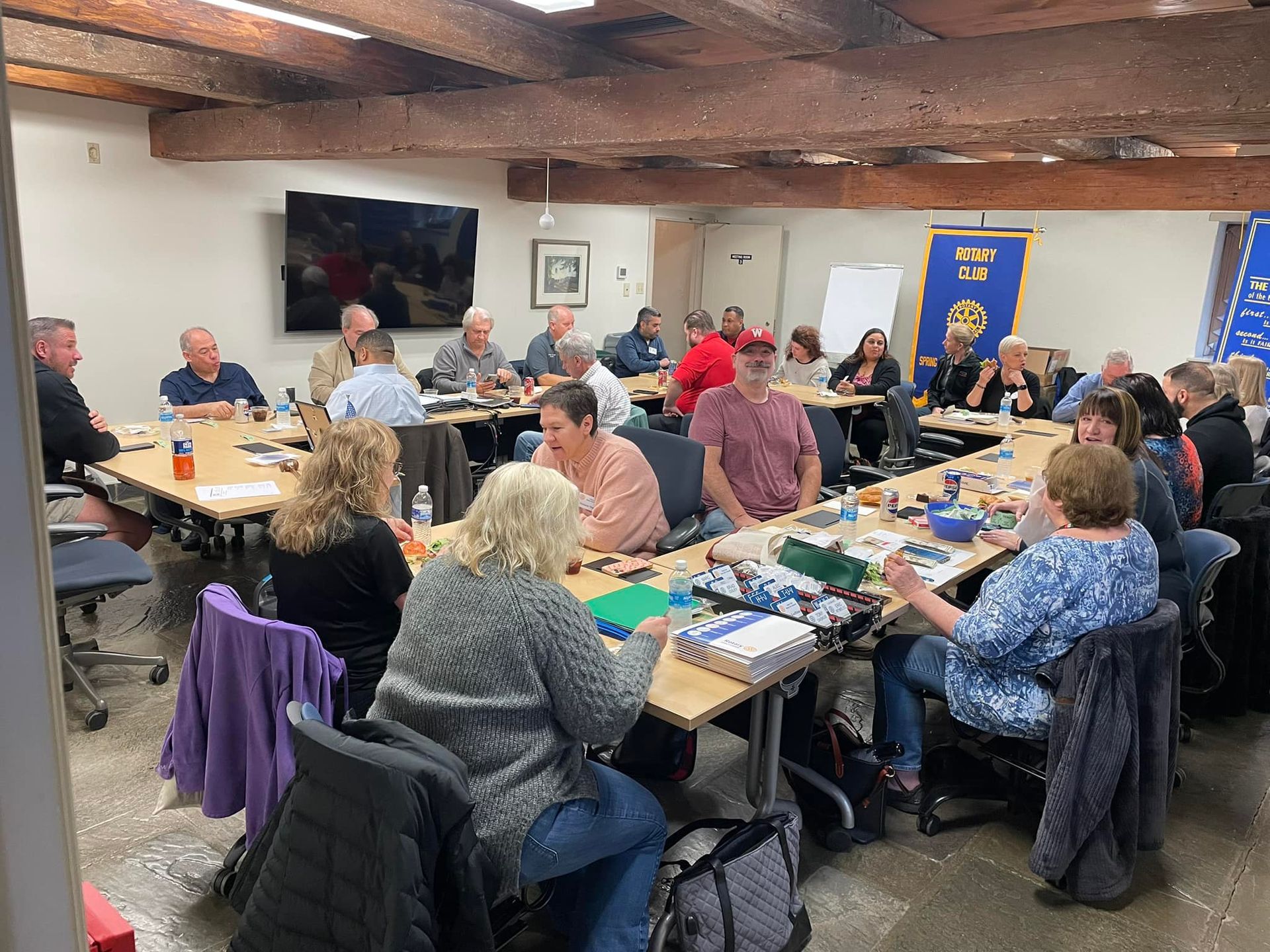 A group of people are sitting around tables in a room.