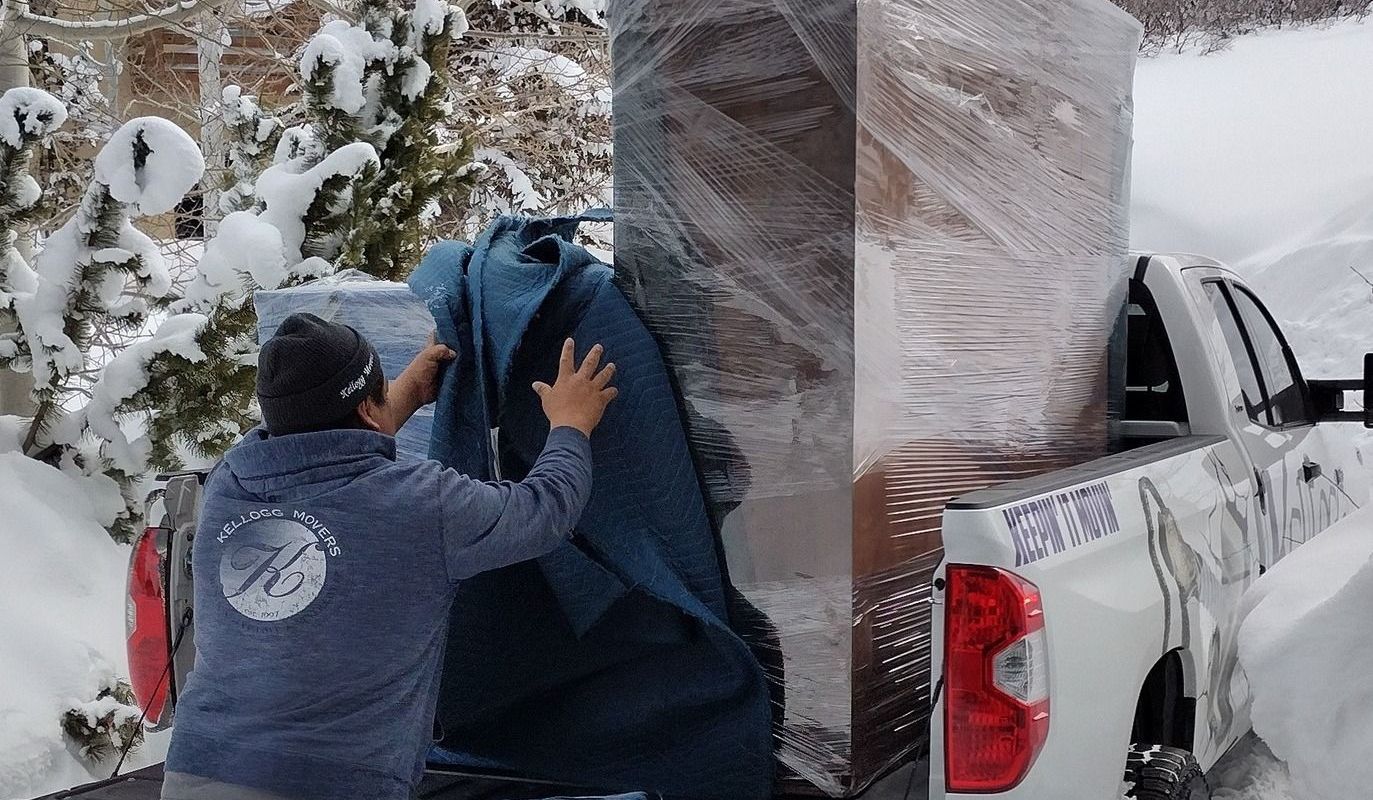 A man is loading a large box into the back of a truck.