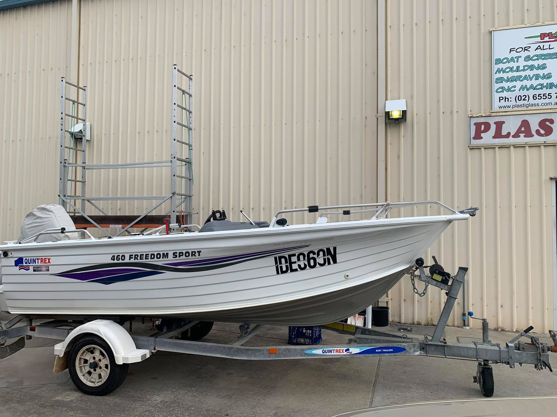 A boat on a trailer is parked in front of a building.