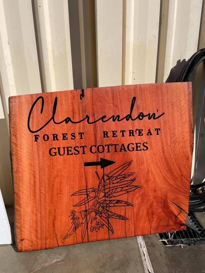 A wooden sign for clarendon forest retreat guest cottages