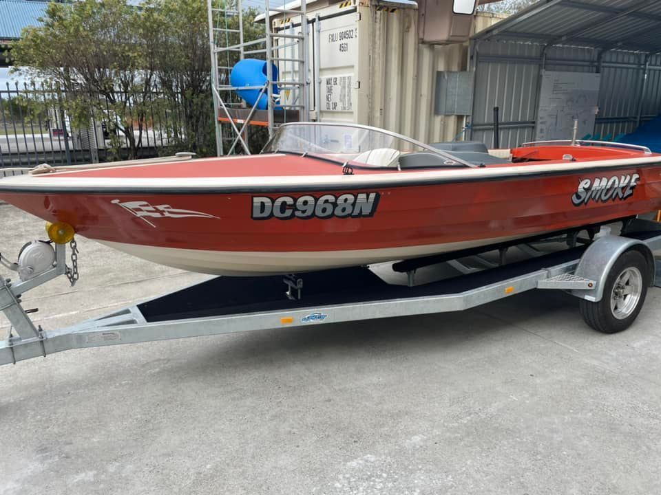A red boat with the license plate dc968n is on a trailer.