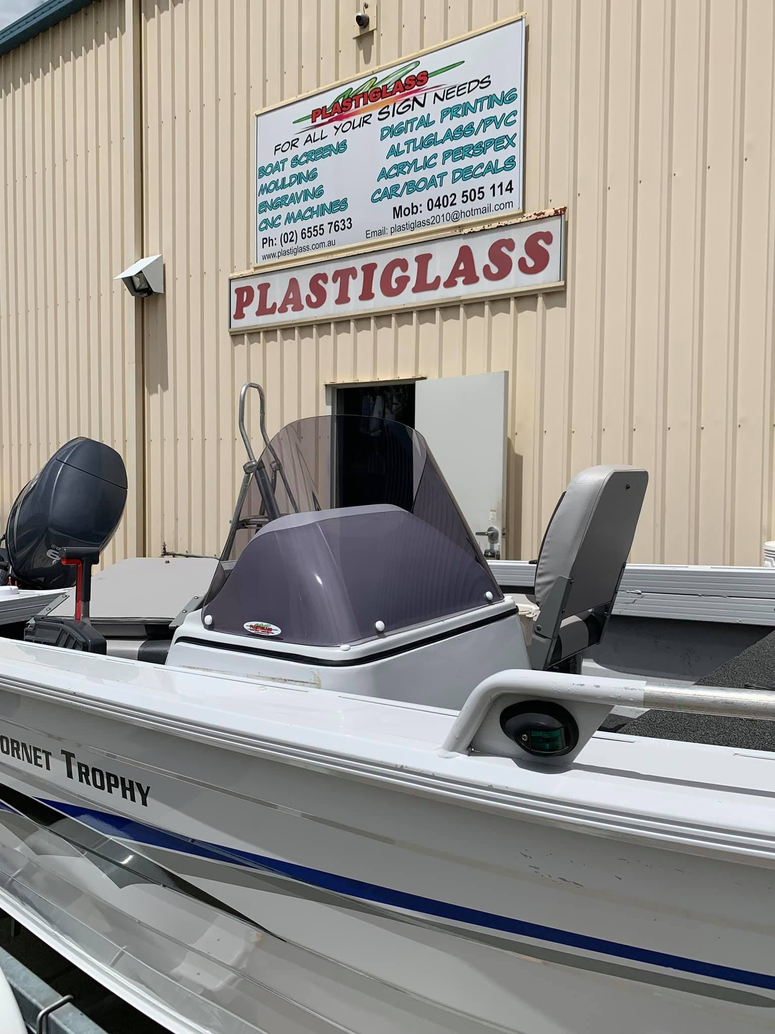A boat is parked in front of a building with a sign that says plasticglass.