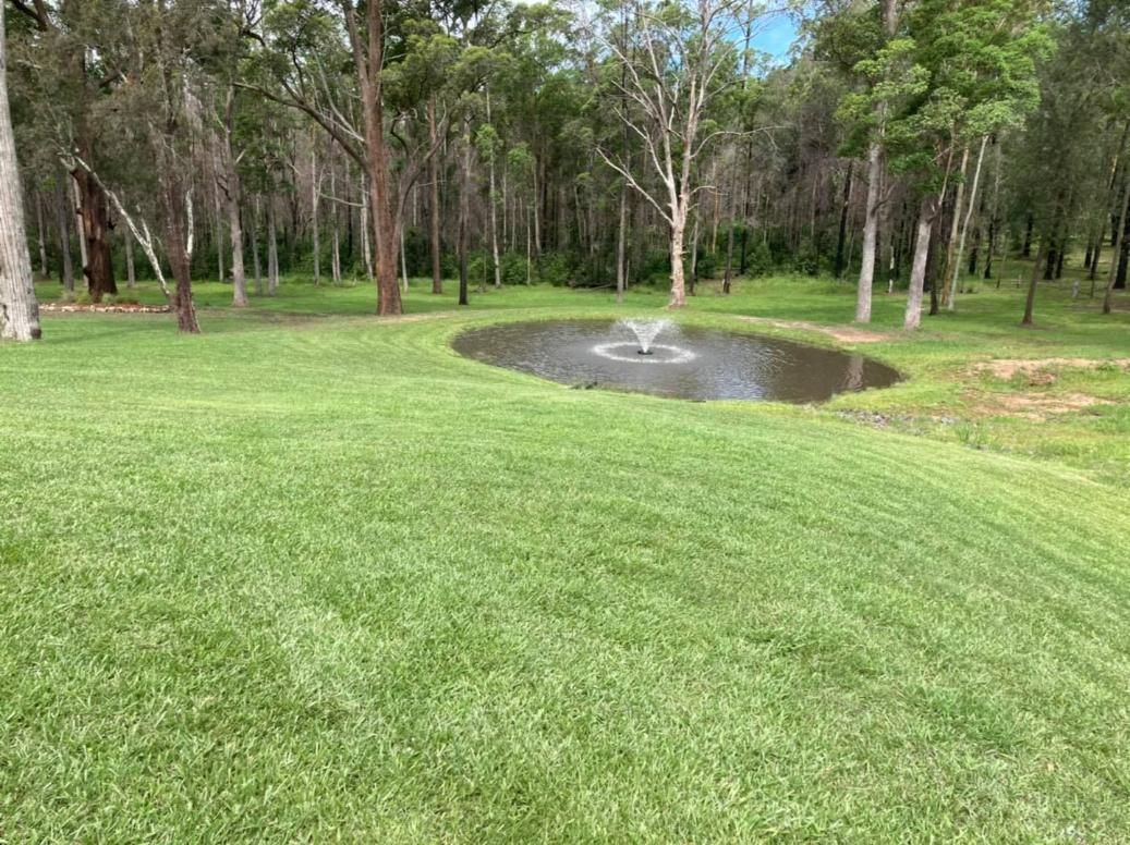 A Small Pond With A Fountain In The Middle Of A Lush Green Field — United Funeral Care In Kempsey, NSW