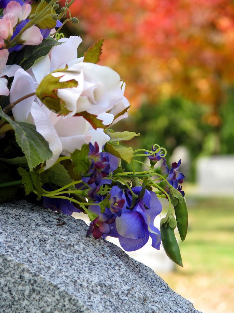 A Bunch Of Flowers Are Sitting On A Grave In A Cemetery — United Funeral Care In Kempsey, NSW