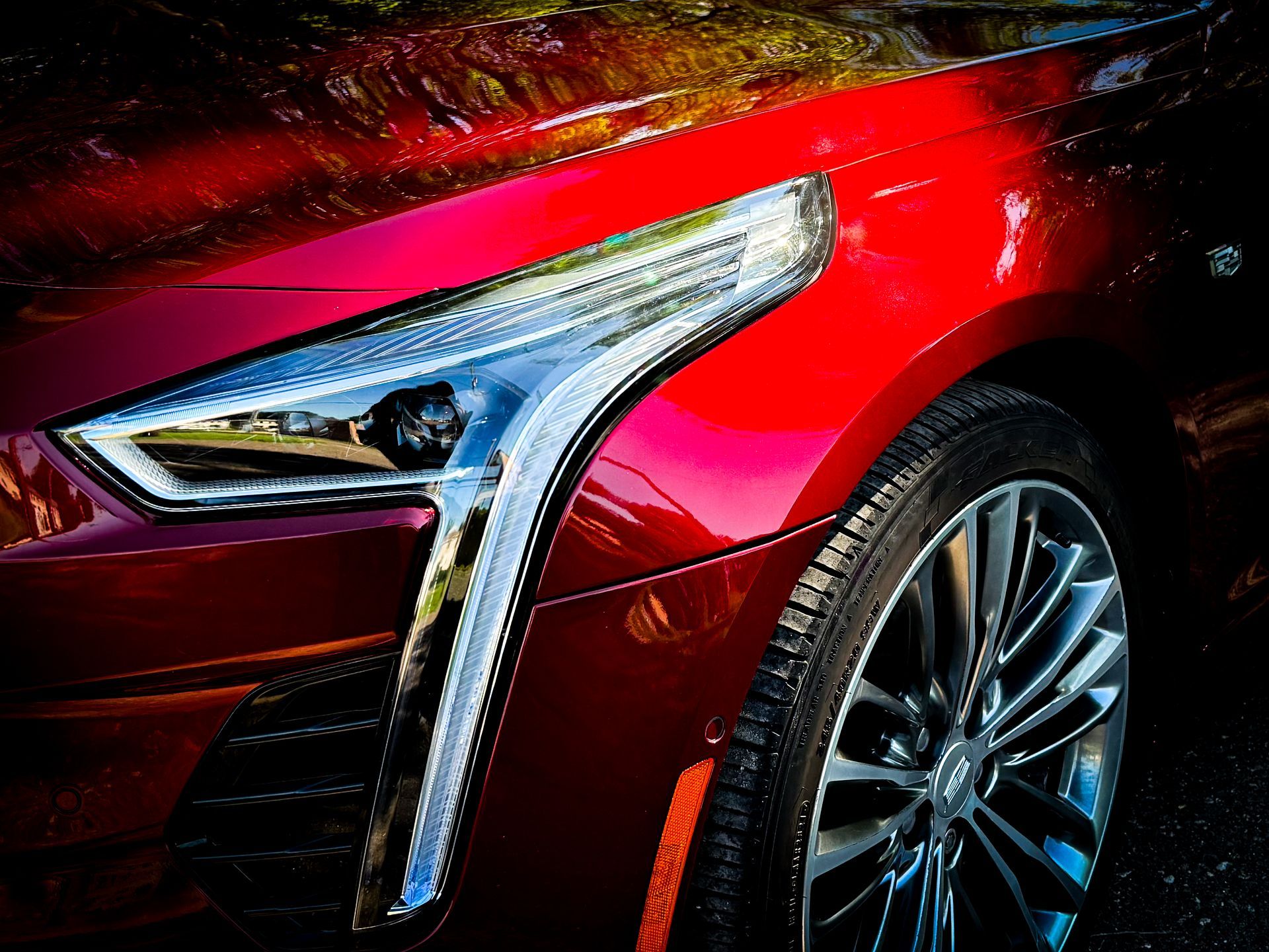A close up of a red car 's headlight and fender.