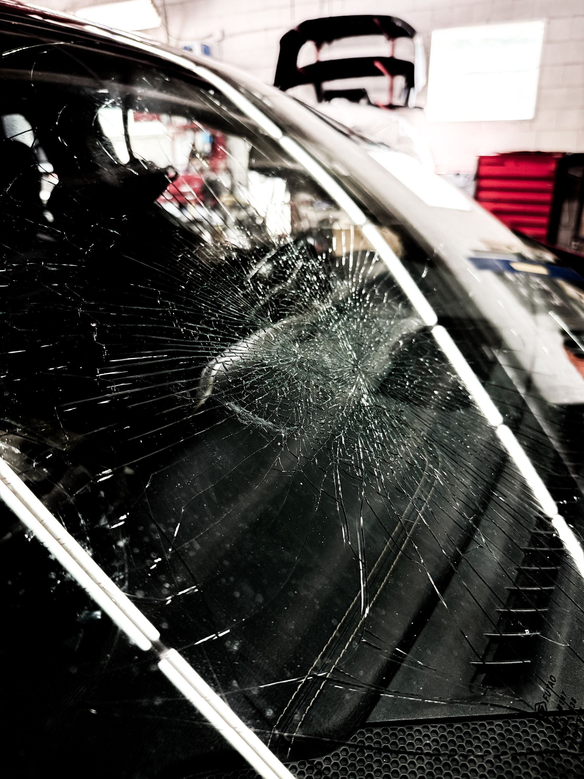 A car with a broken windshield in a garage