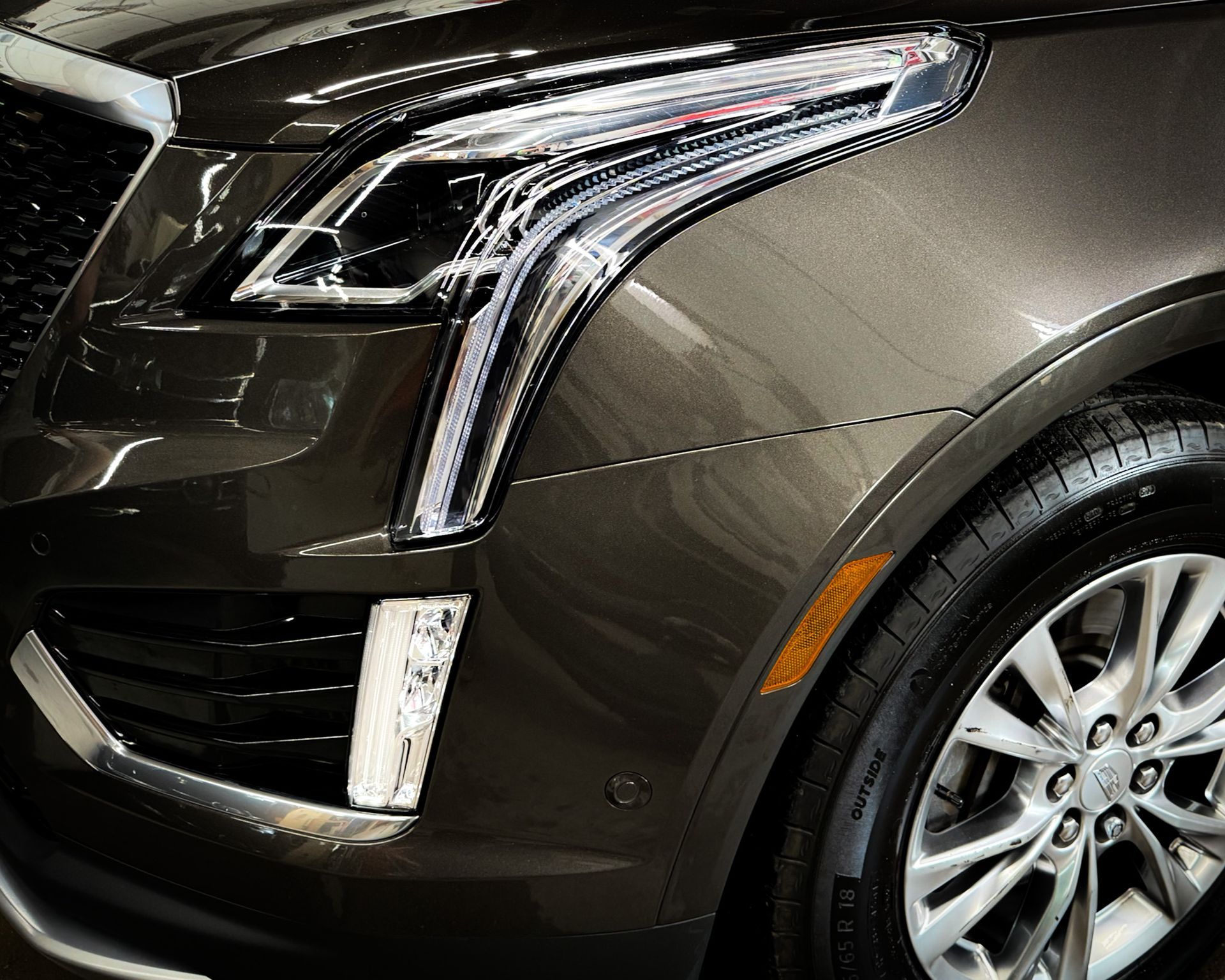 A close up of a car 's headlight and tire
