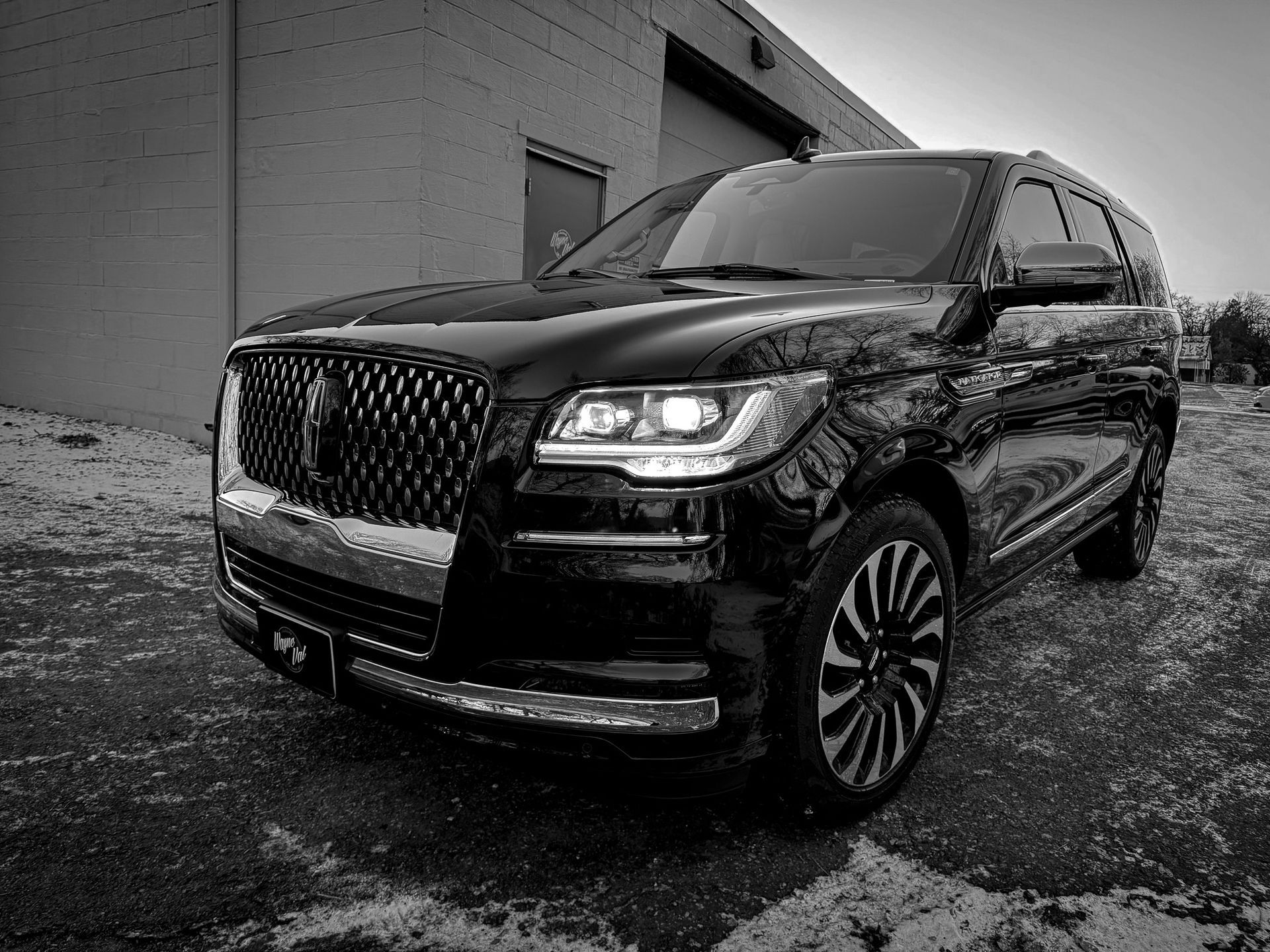 A black and white photo of a lincoln navigator parked in front of a building.