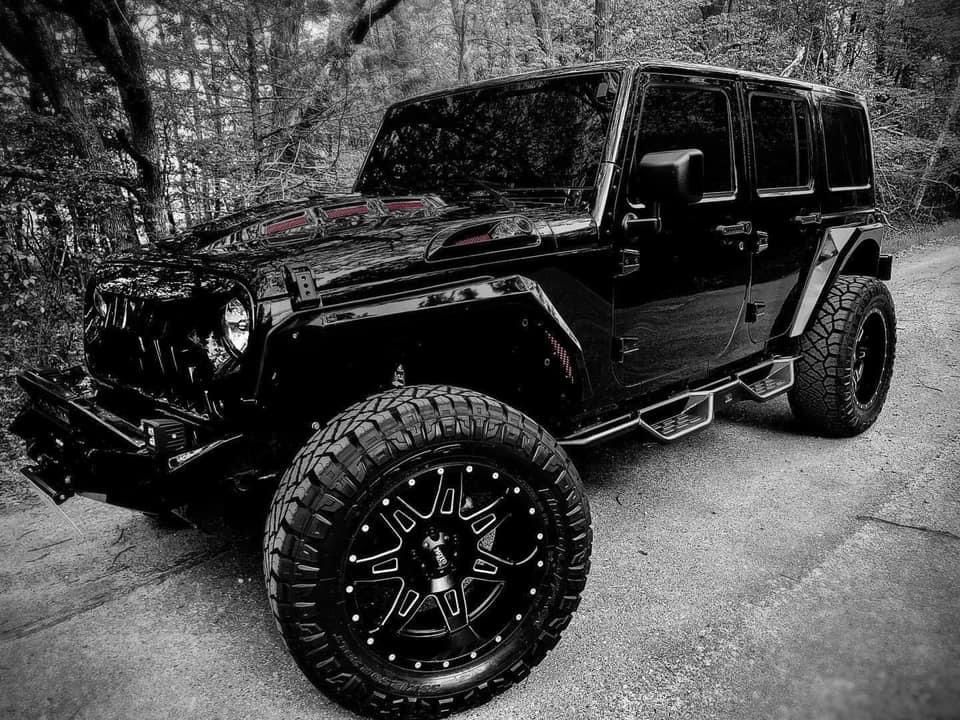 A black and white photo of a black jeep parked on the side of a road.