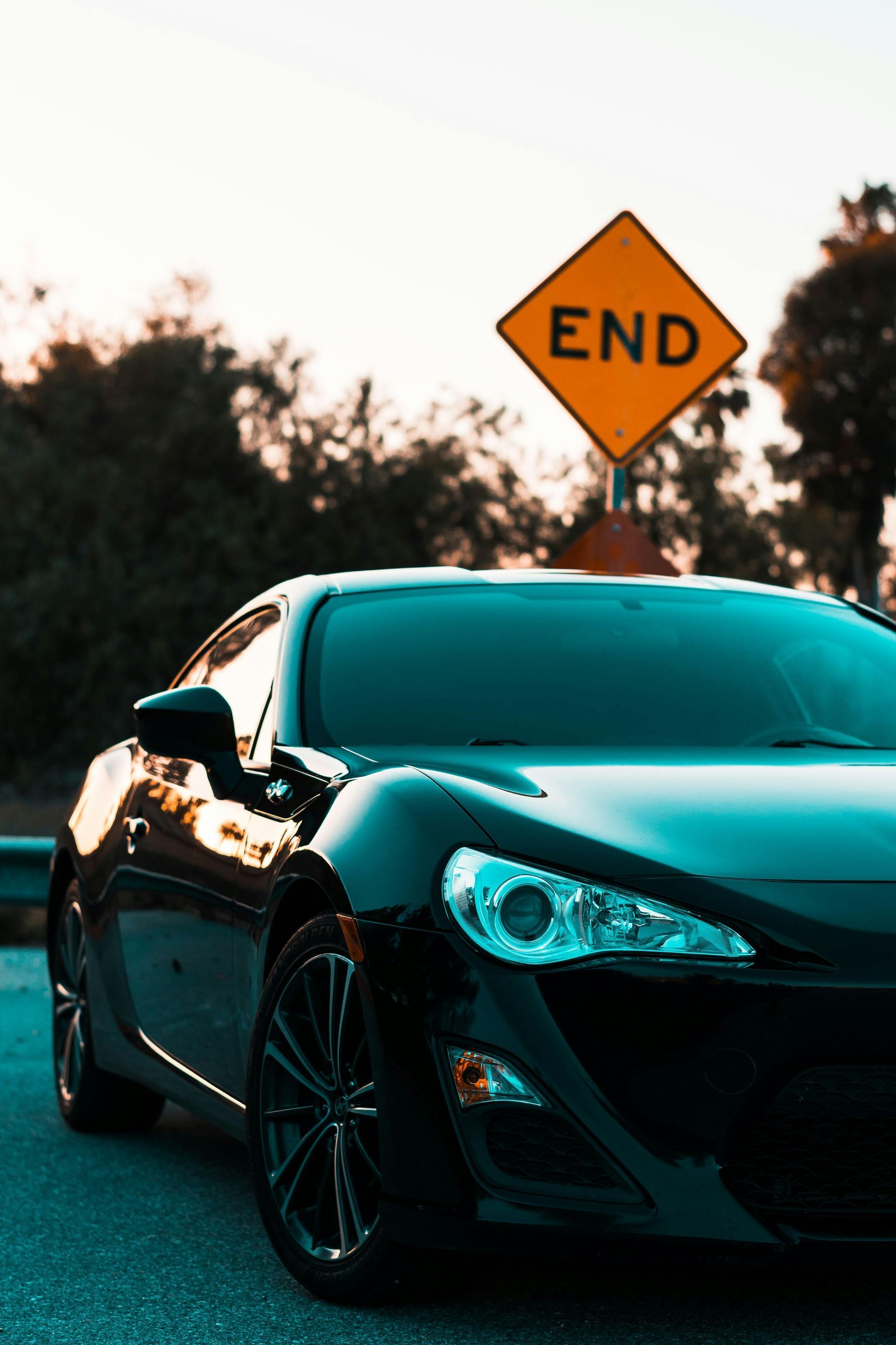 A black car is parked in front of an end sign