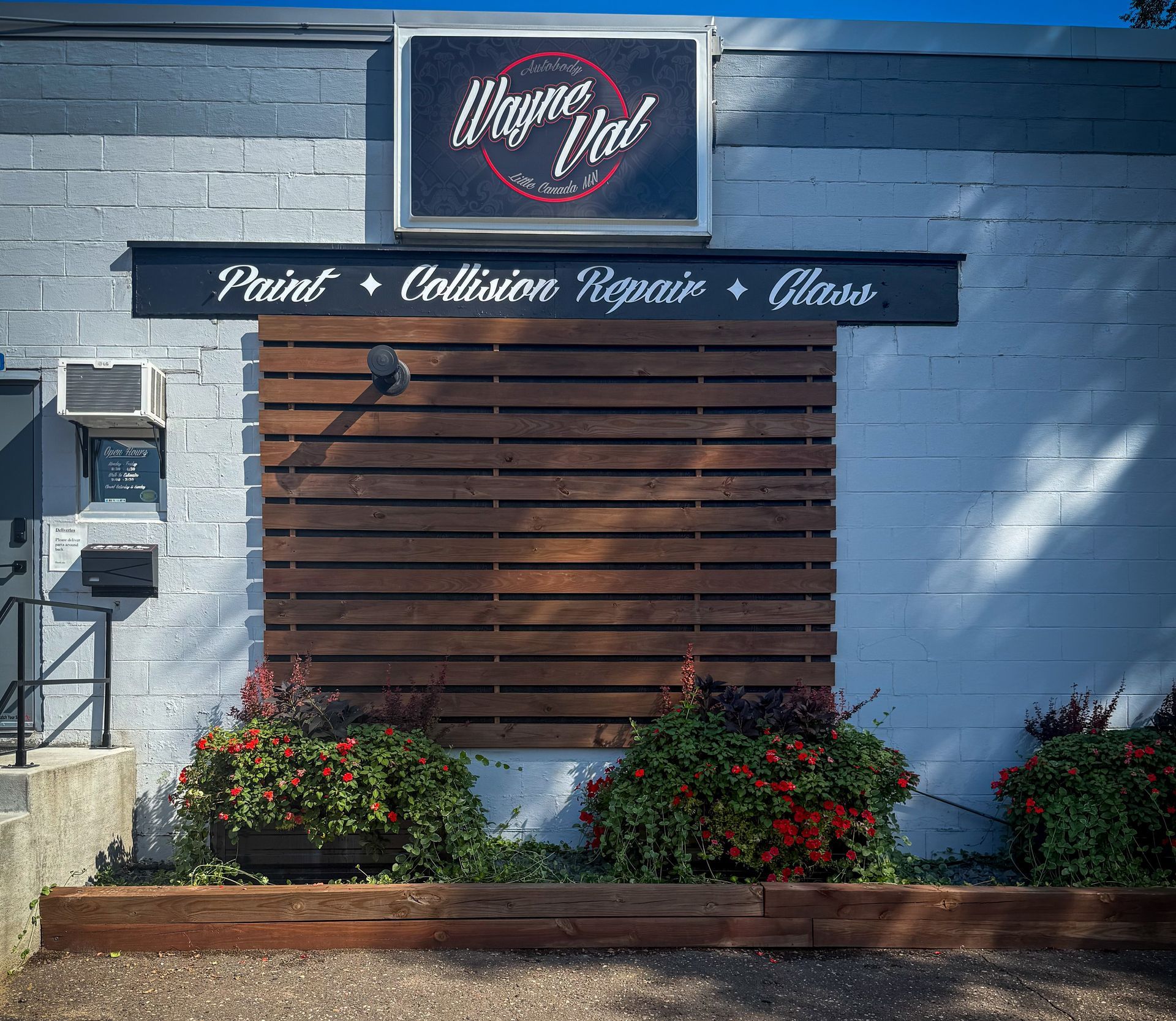Exterior of Wayne Val auto shop with sign and services listed: Paint, Collision Repair, Glass.