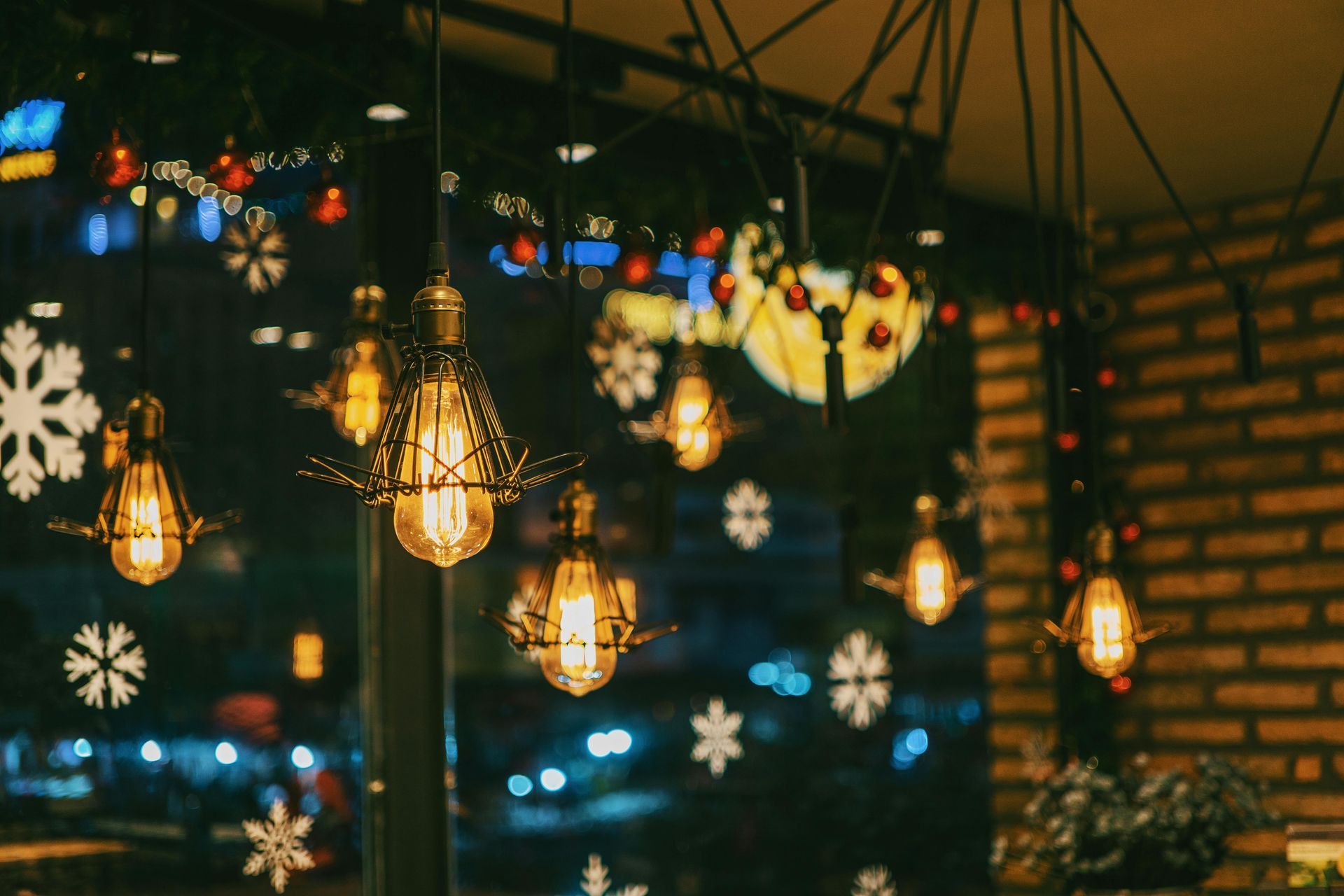Lights hang in a room with snowflake decorations, reflecting on window with city lights.