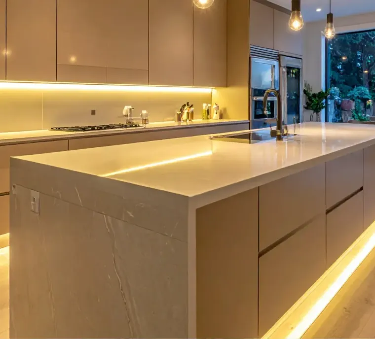 Modern kitchen with large island, warm under-cabinet lighting, and floor-to-ceiling windows overlooking greenery
