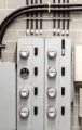 Gray electrical breaker panels and conduit mounted on a cinderblock wall in an industrial room
