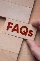 Hand placing a red “FAQs” tile into a wooden puzzle board opening