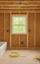 Unfinished bathroom with exposed studs, bathtub, window, and electrical wiring during renovation