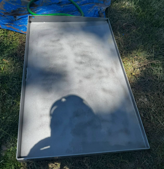 A stainless steel tray is sitting on top of a grass covered field.