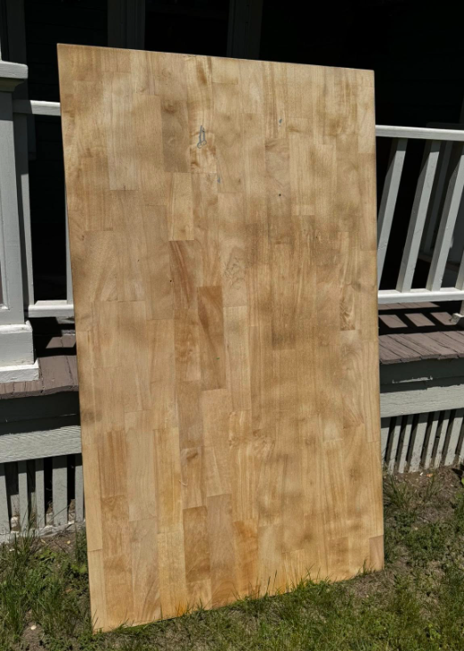 A large piece of wood is sitting on top of a lush green field.