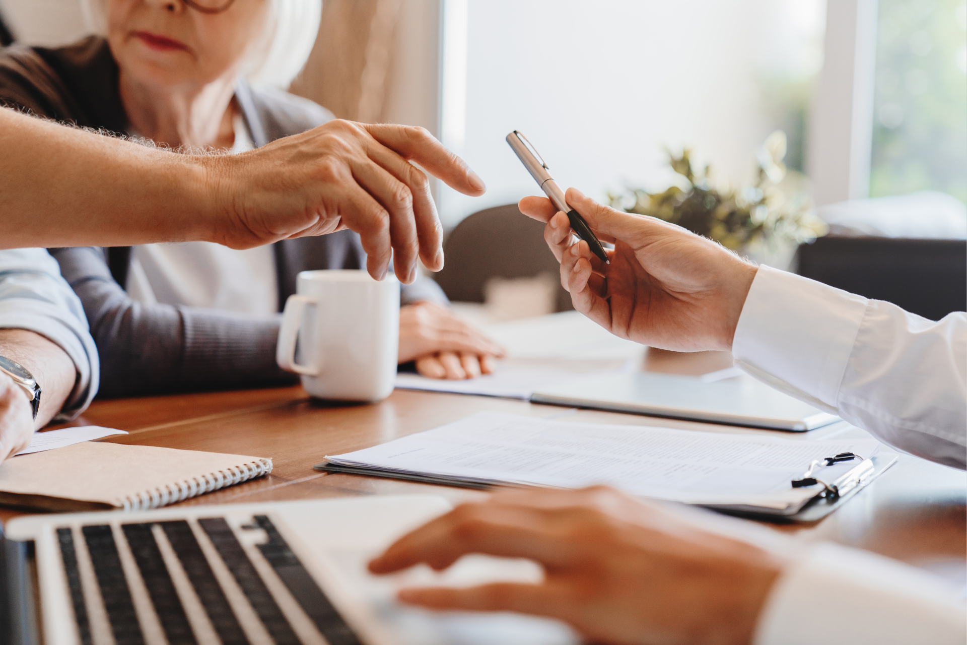 A group of people are sitting at a table with a laptop and a cup of coffee.