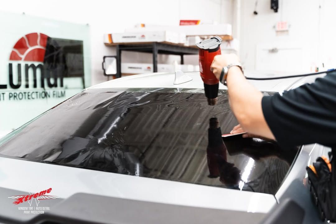 A man is applying window tinting to the window of a car.