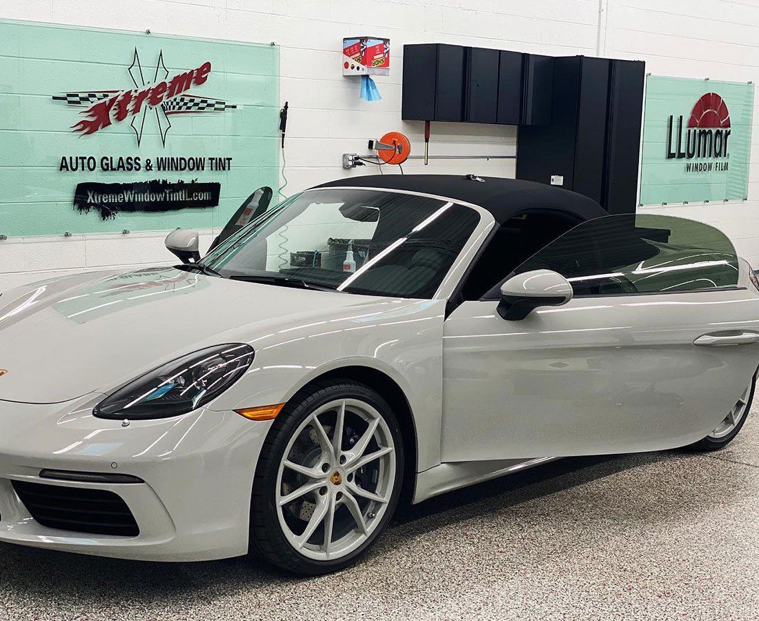 a white porsche boxster convertible is parked in a garage .