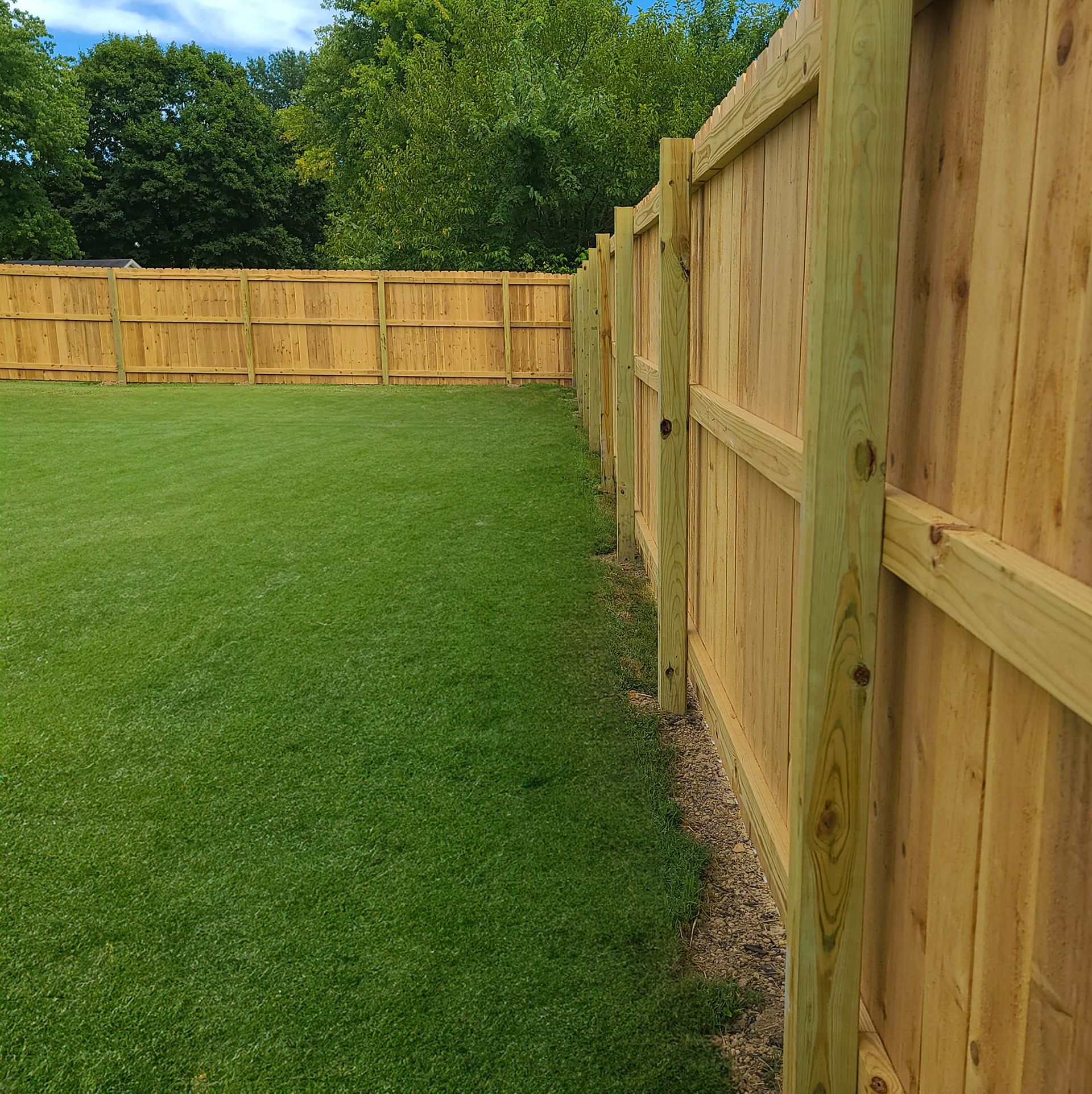 Red Beaver Construction team member standing next to a completed fence project.