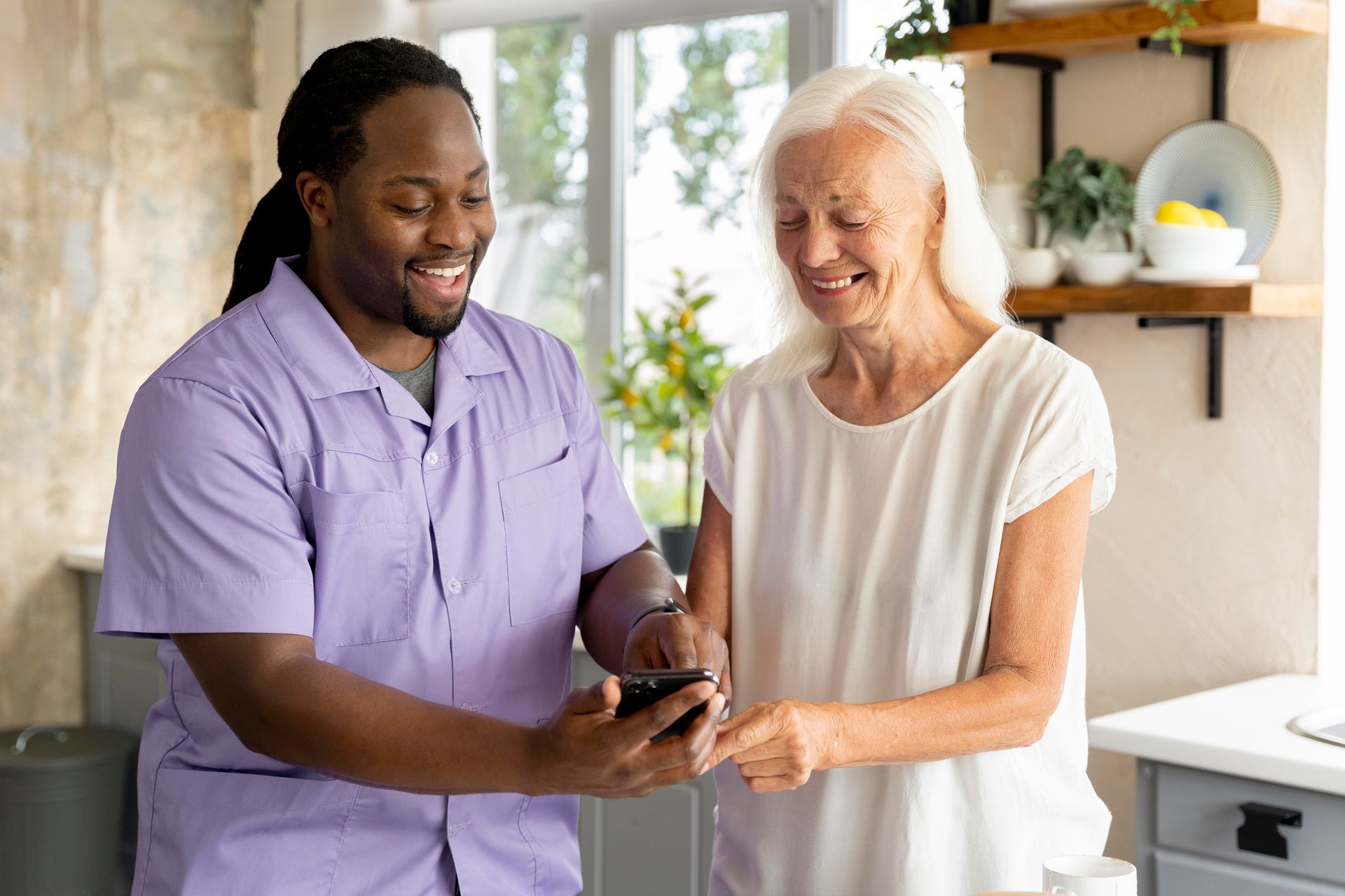 A man is helping an elderly woman use a cell phone.