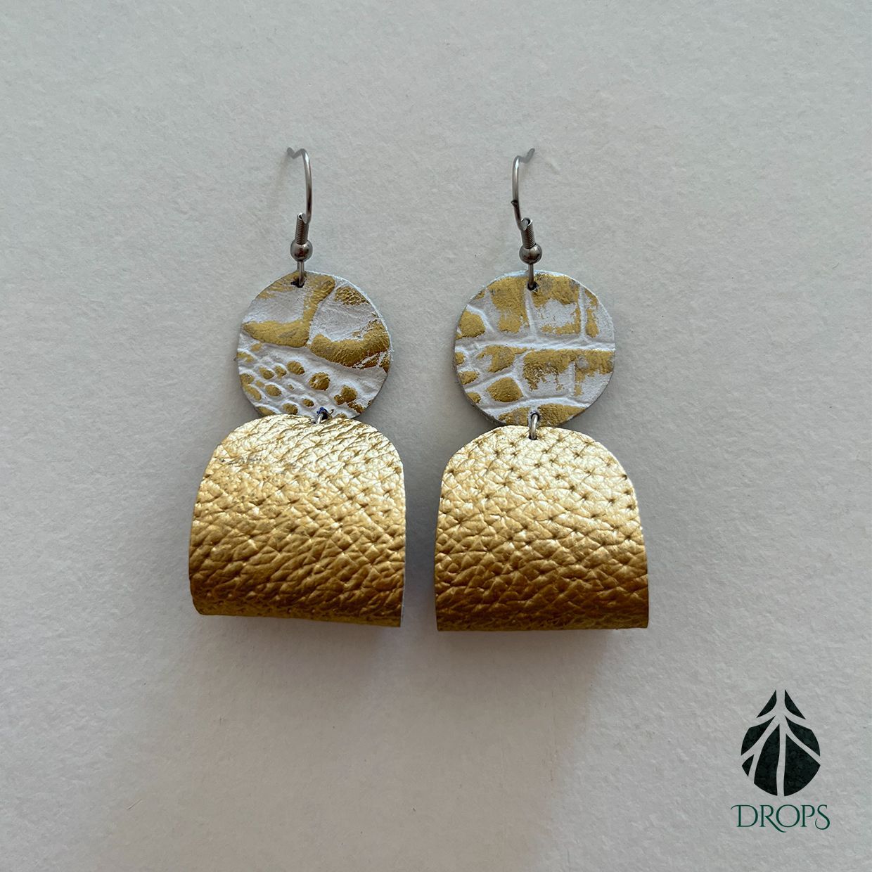Un par de pendientes de oro y plata hechos con gotas.