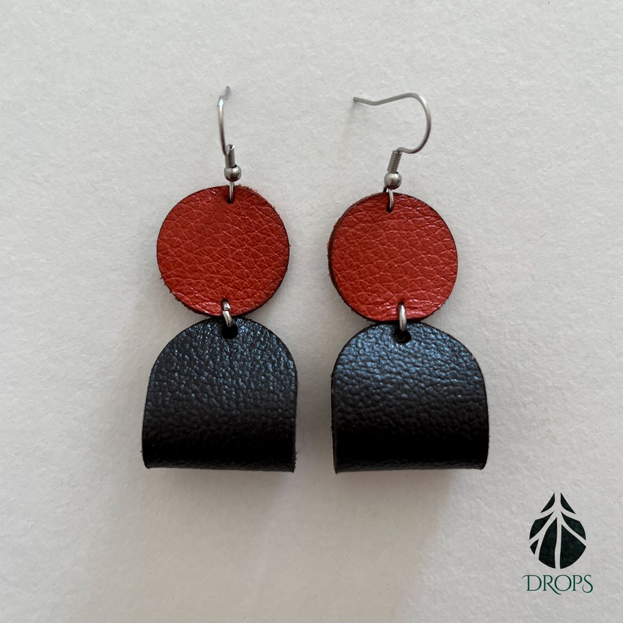 Un par de pendientes negros y rojos hechos con gotas.