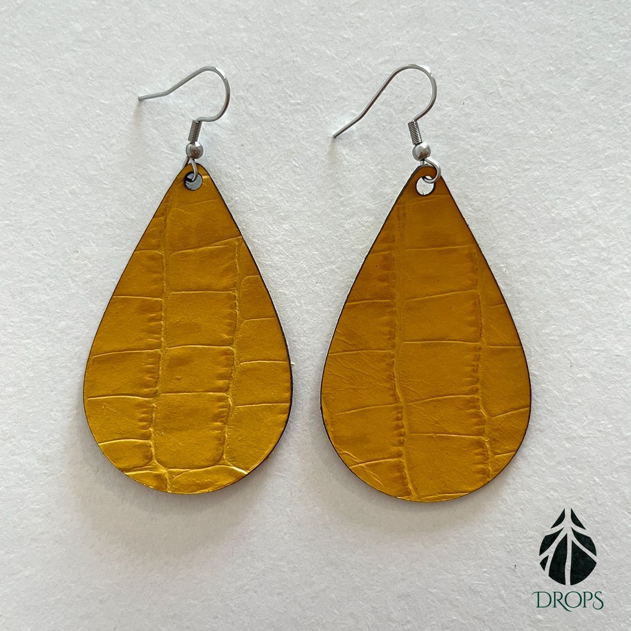 Un par de pendientes dorados en forma de lágrima hechos con gotas.