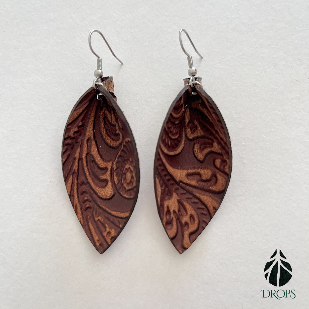 Un par de pendientes marrones en forma de hoja hechos con gotas.