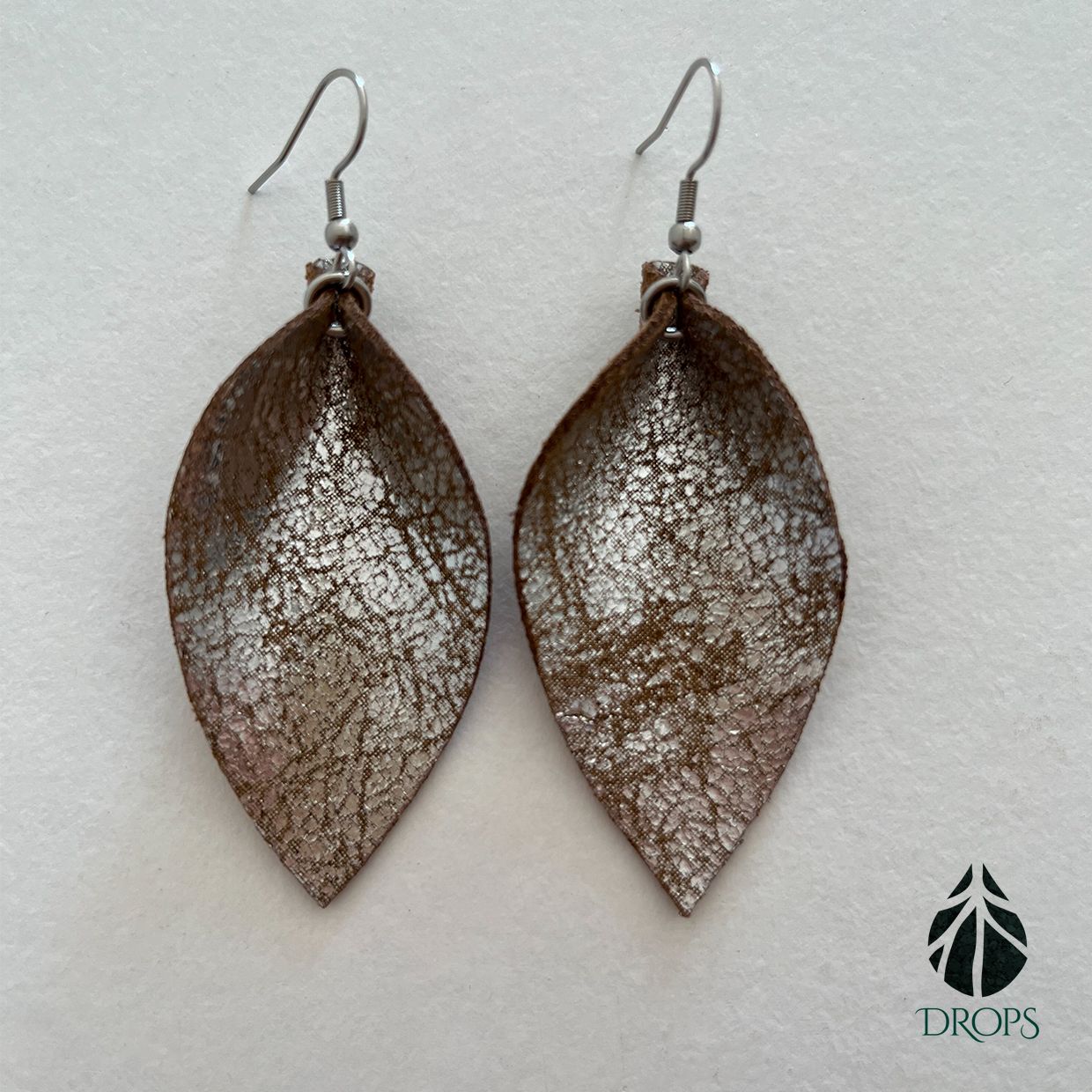 Un par de pendientes marrones en forma de hoja hechos con gotas.