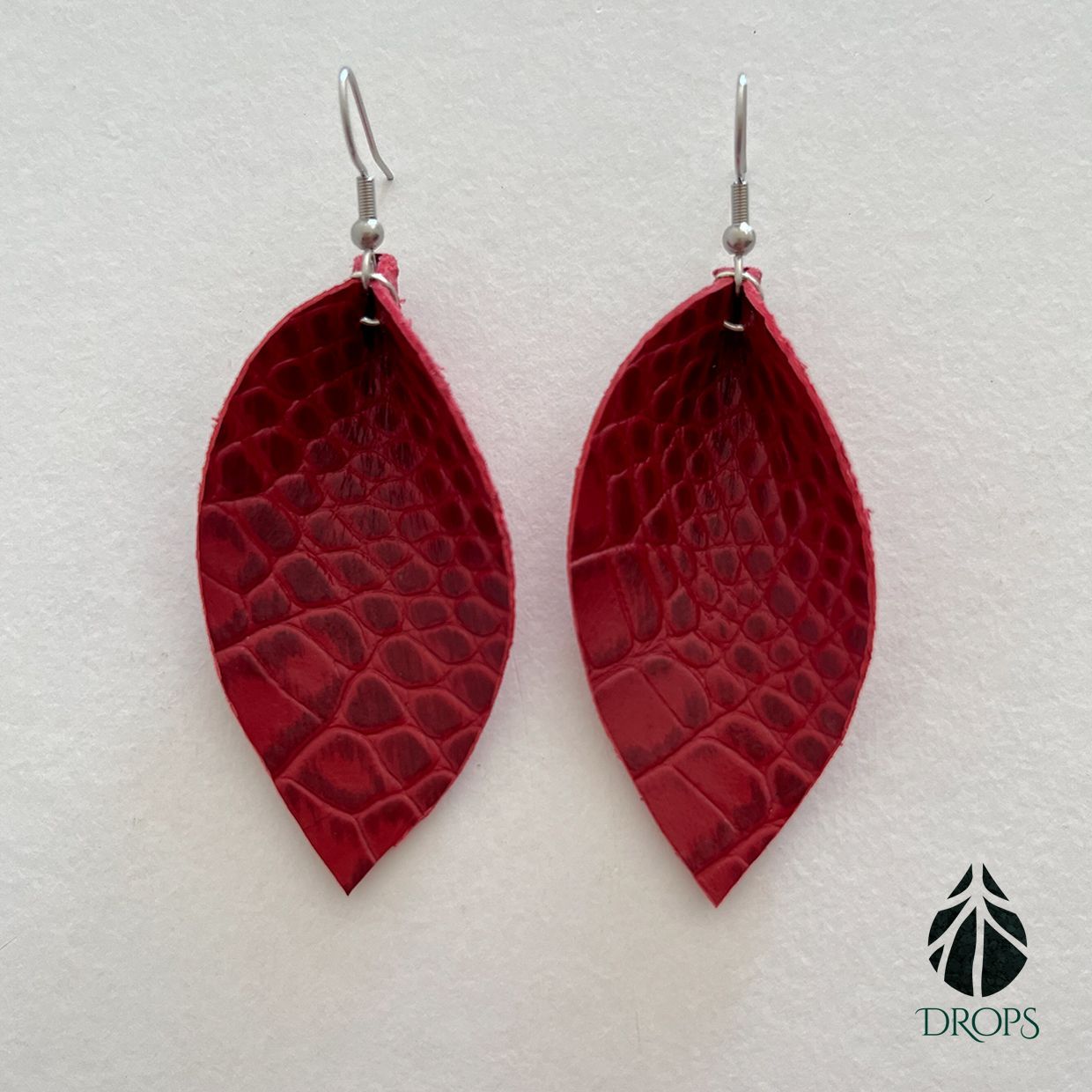 Un par de pendientes en forma de hoja roja hechos con gotas.