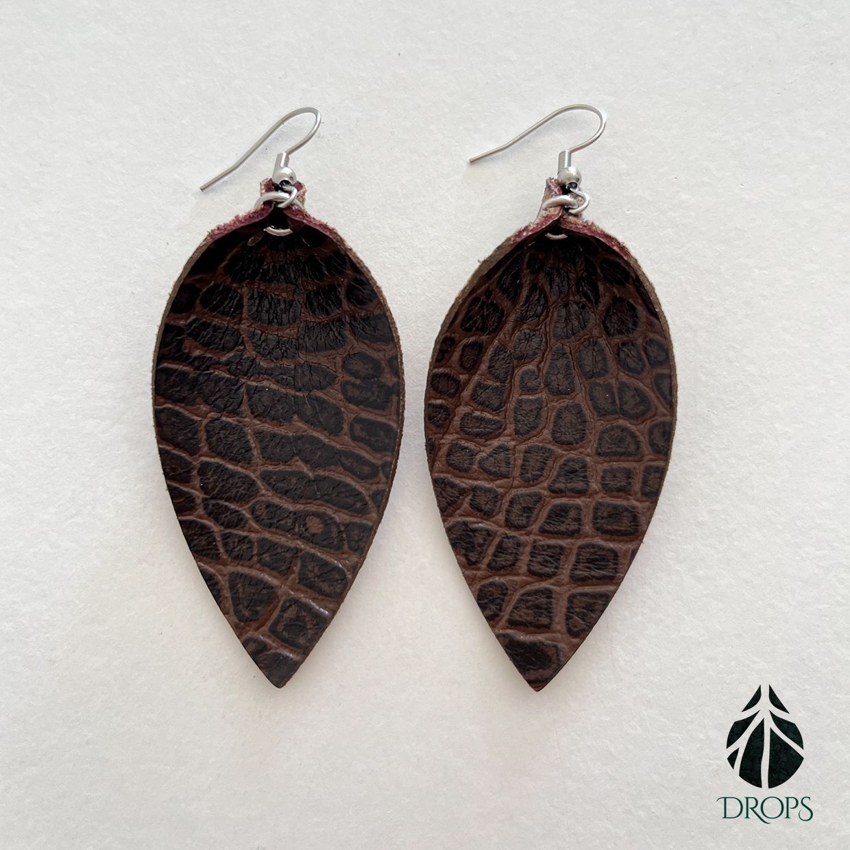 Un par de pendientes marrones en forma de hoja hechos con gotas.