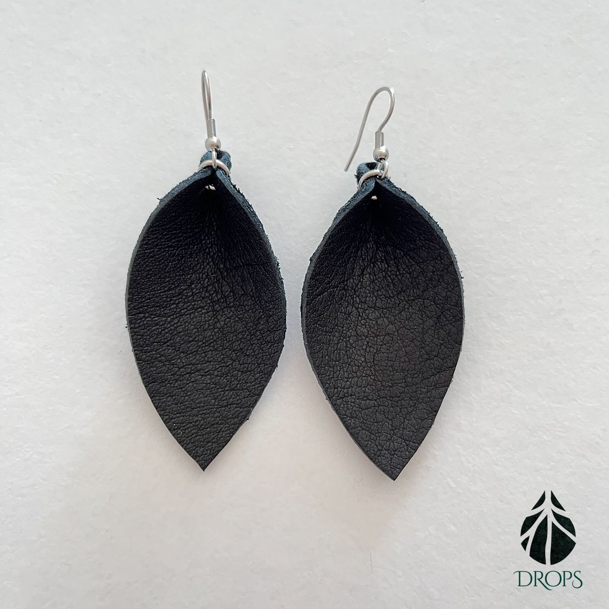 Un par de pendientes negros en forma de hoja hechos con gotas.