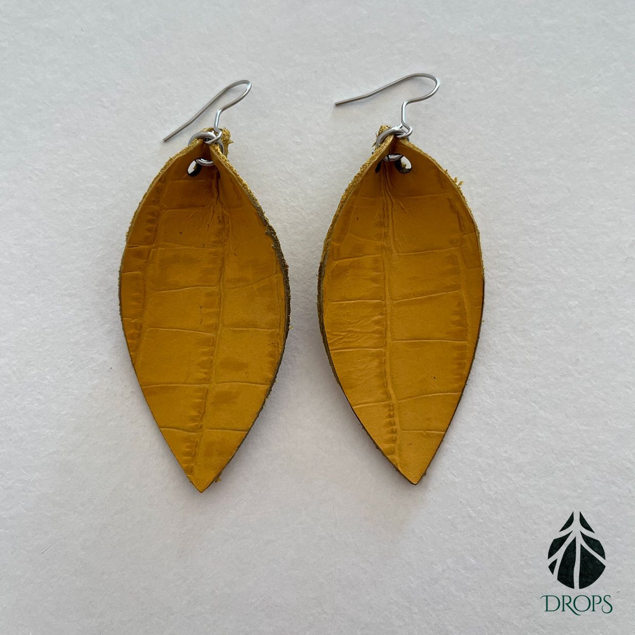 Un par de pendientes en forma de hoja amarilla hechos con gotas.