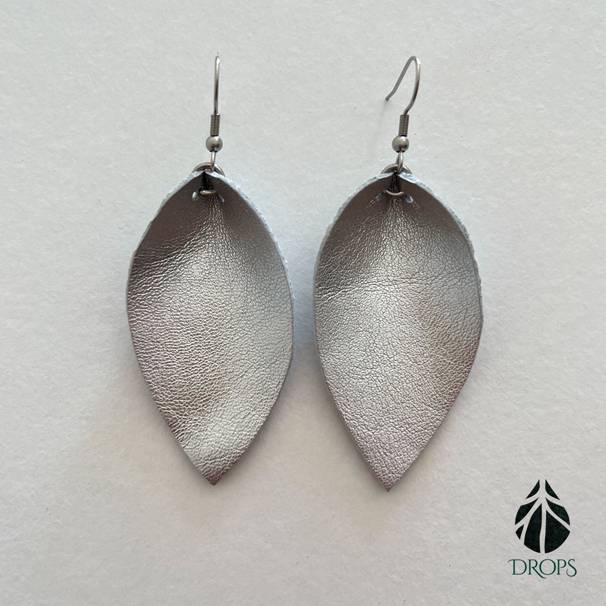 Un par de pendientes en forma de hoja de plata hechos con gotas.