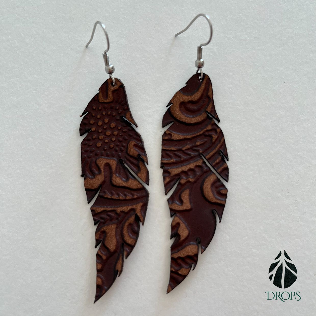 Un par de pendientes con forma de pluma marrón hechos con gotas.