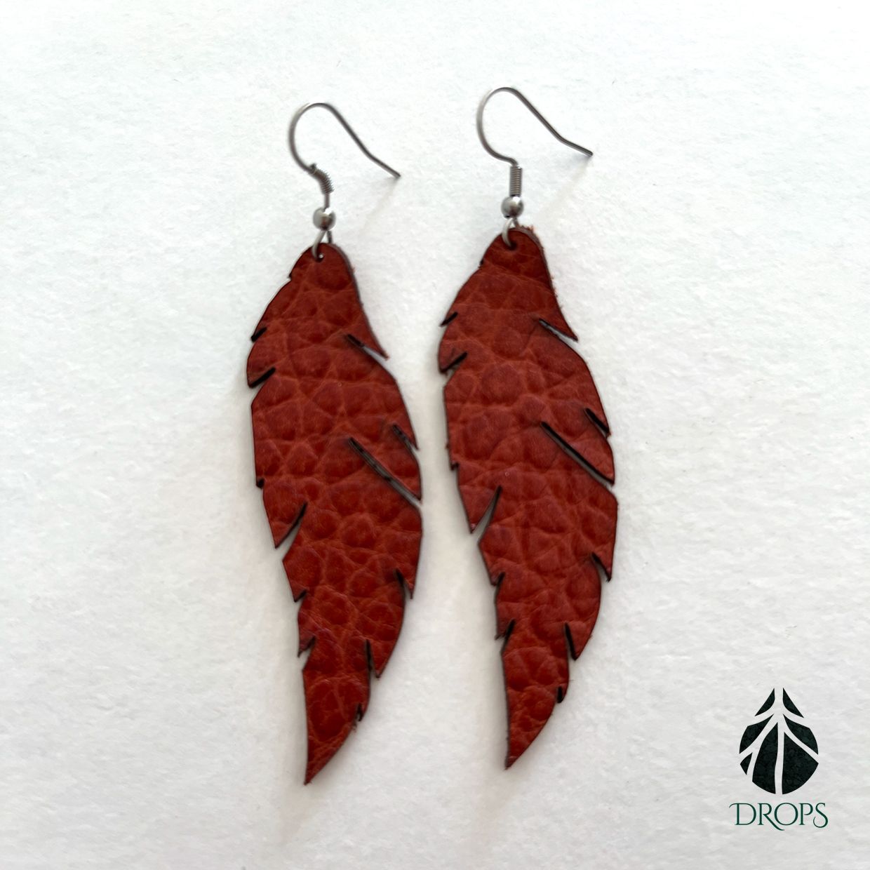 Un par de pendientes con forma de pluma roja de drops