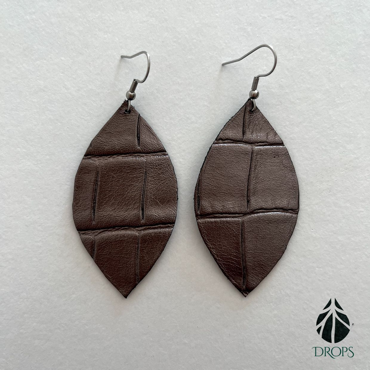 Un par de pendientes marrones en forma de hoja hechos con gotas.