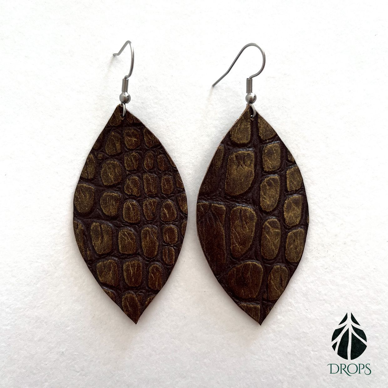 Un par de pendientes marrones en forma de hoja hechos con gotas.