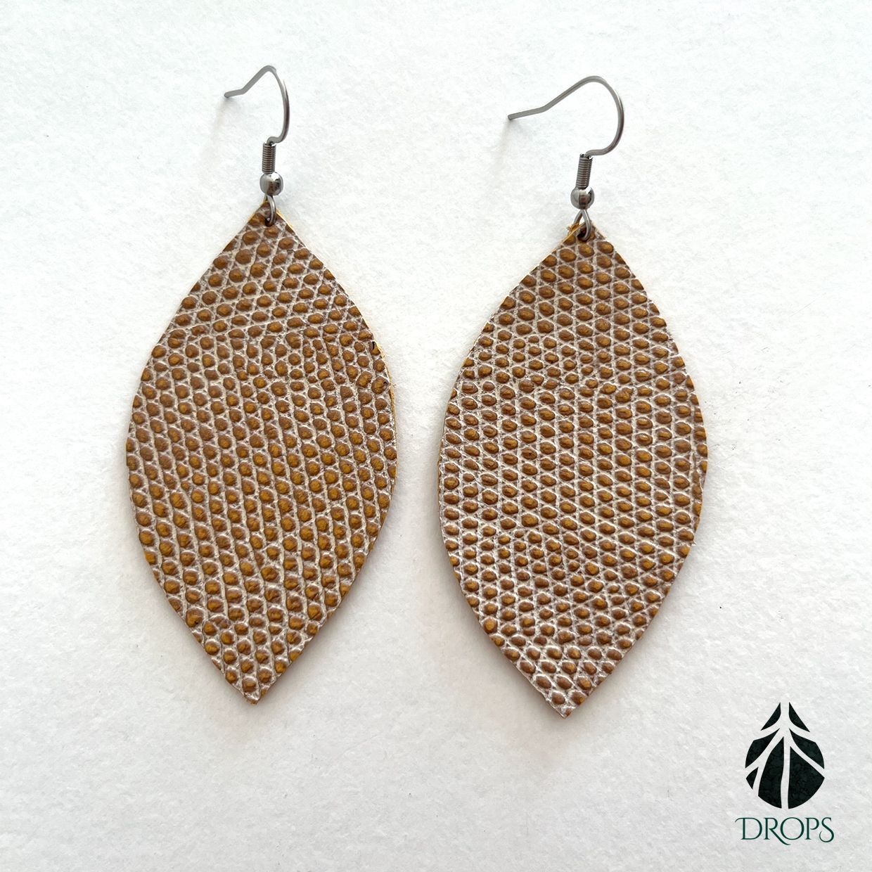 Un par de pendientes marrones en forma de hoja hechos con gotas.