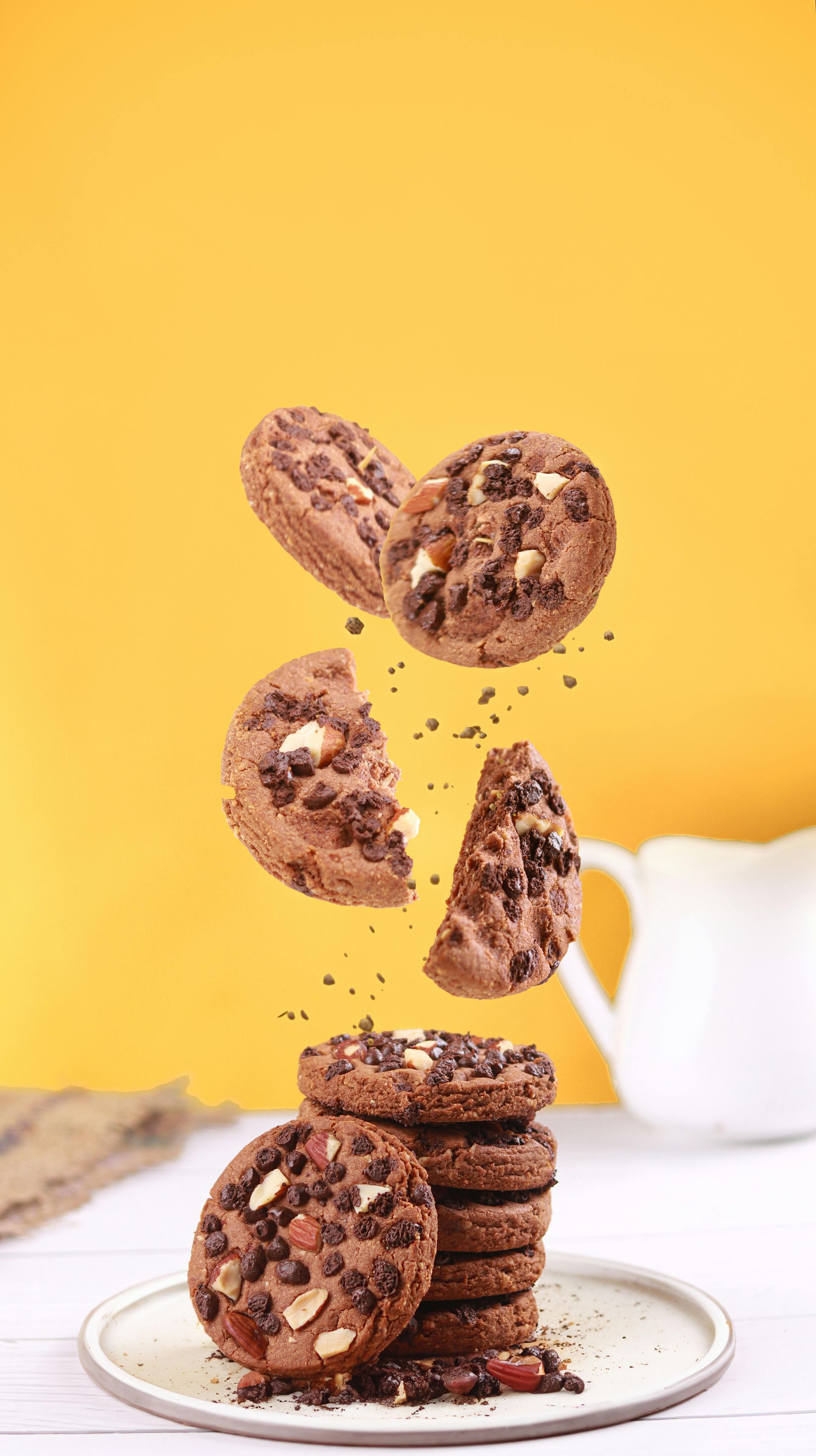 Una pila de galletas con chispas de chocolate con nueces cayendo en un plato. cookies