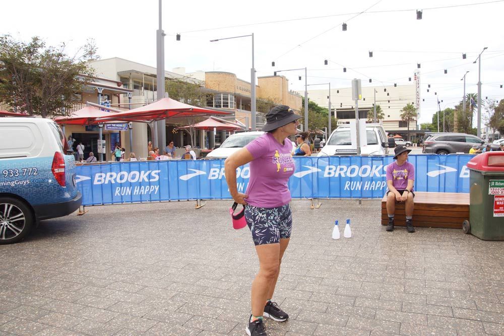 A Woman Is Standing In Front Of A Brooks Sign — Run Fest in Port Macquarie, NSW