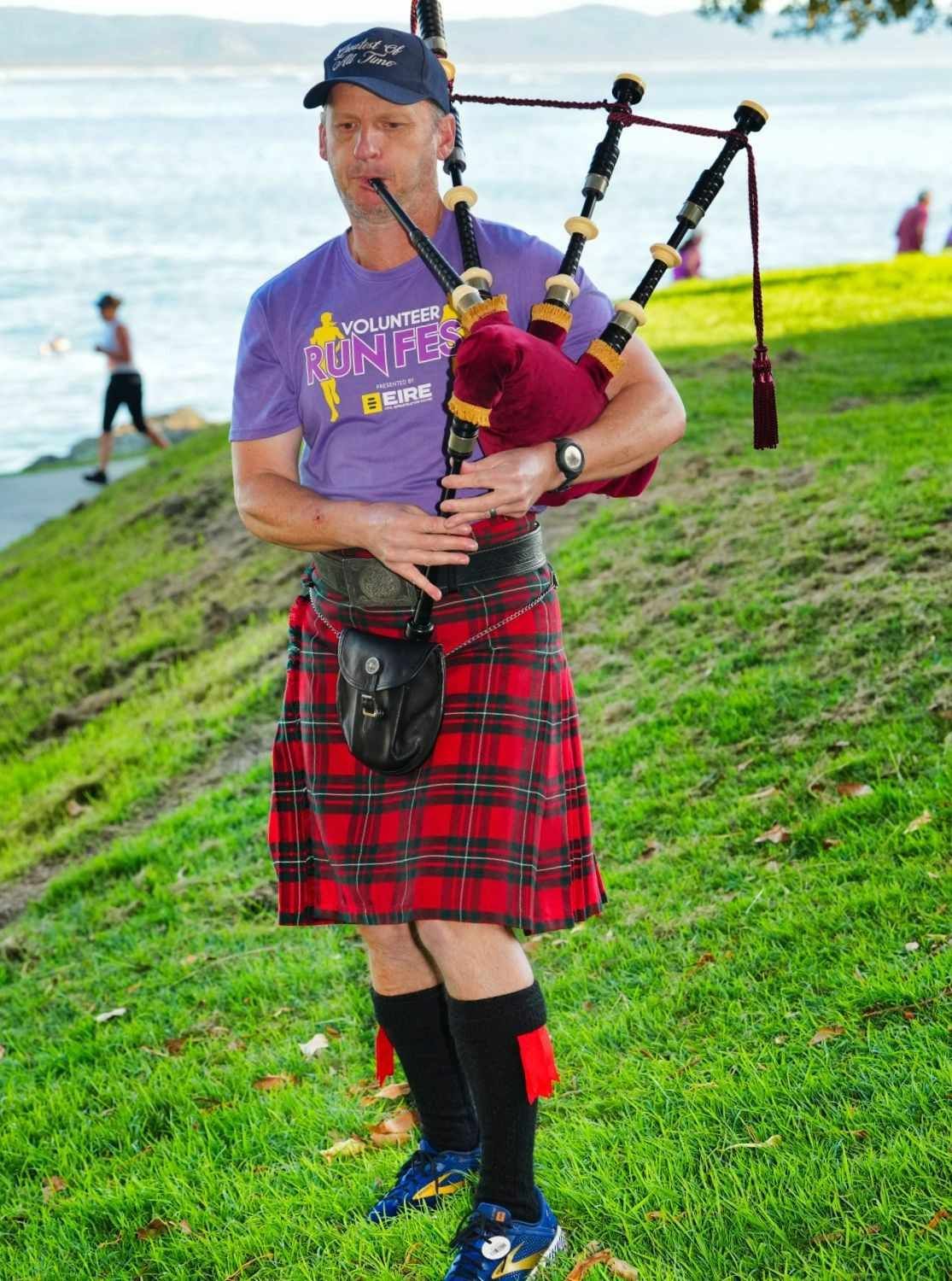 Man in Kilt Plays Bagpipes on A Grassy Bank by The Water — Run Fest in South West Rocks, NSW