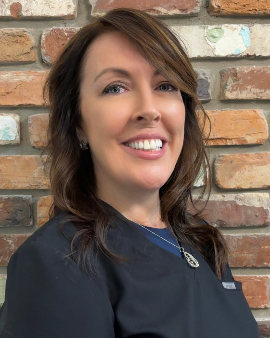 A woman in a blue shirt is smiling for the camera
