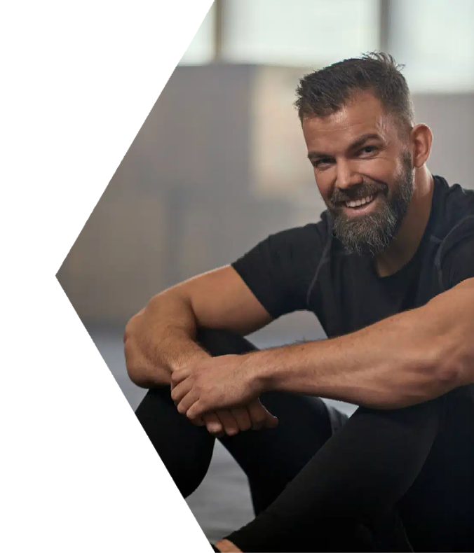 A man with a beard is sitting on the floor and smiling.