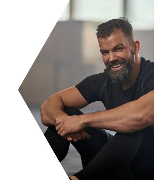 A man with a beard is sitting on the floor and smiling.