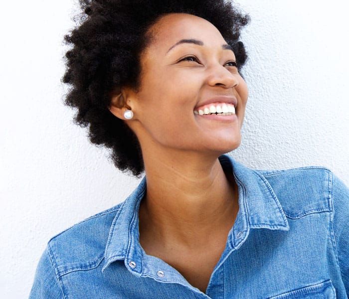 A woman in a denim T-shirt is smiling and looking up